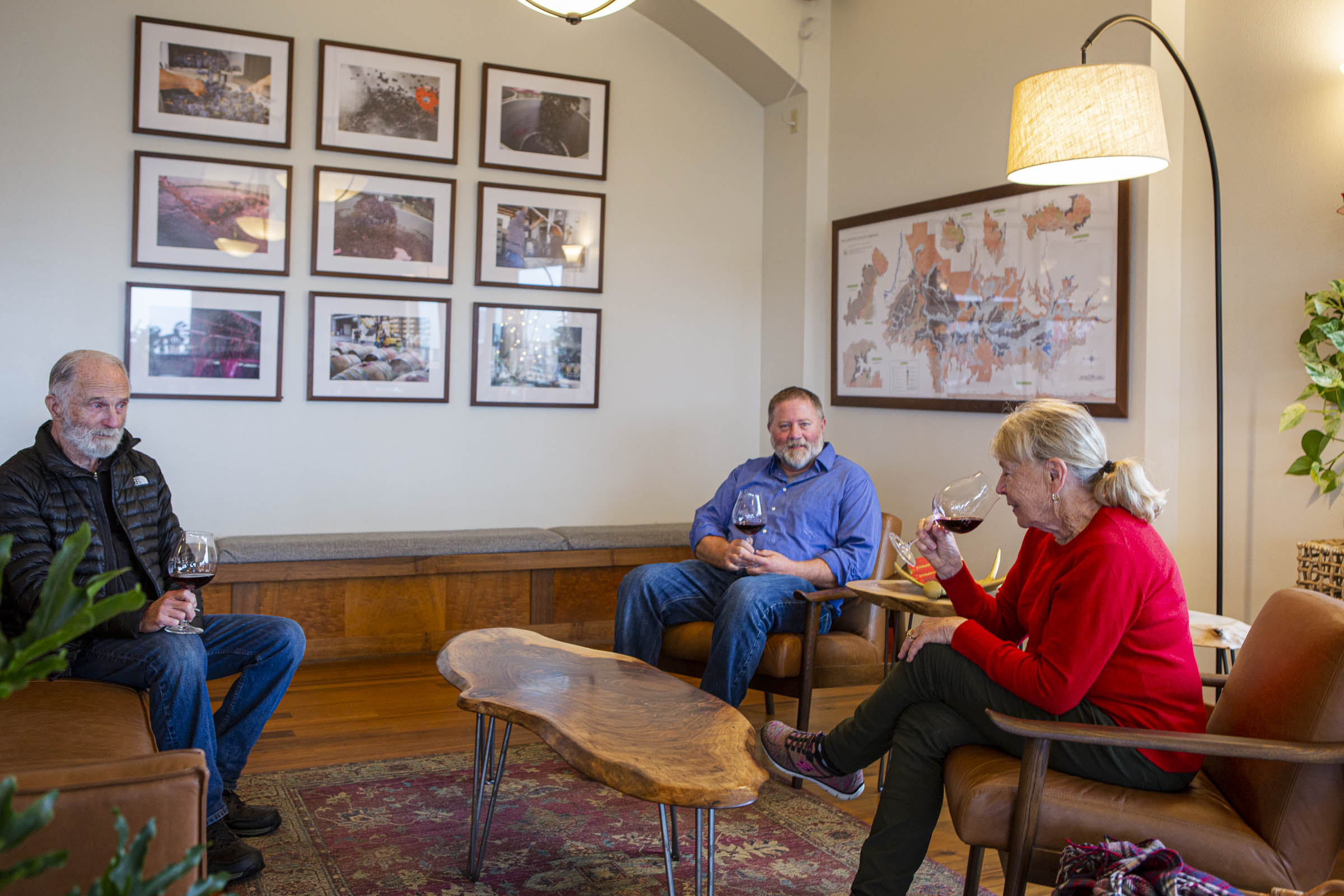 tasting room interior with three people sitting on a couch and lounge chairs