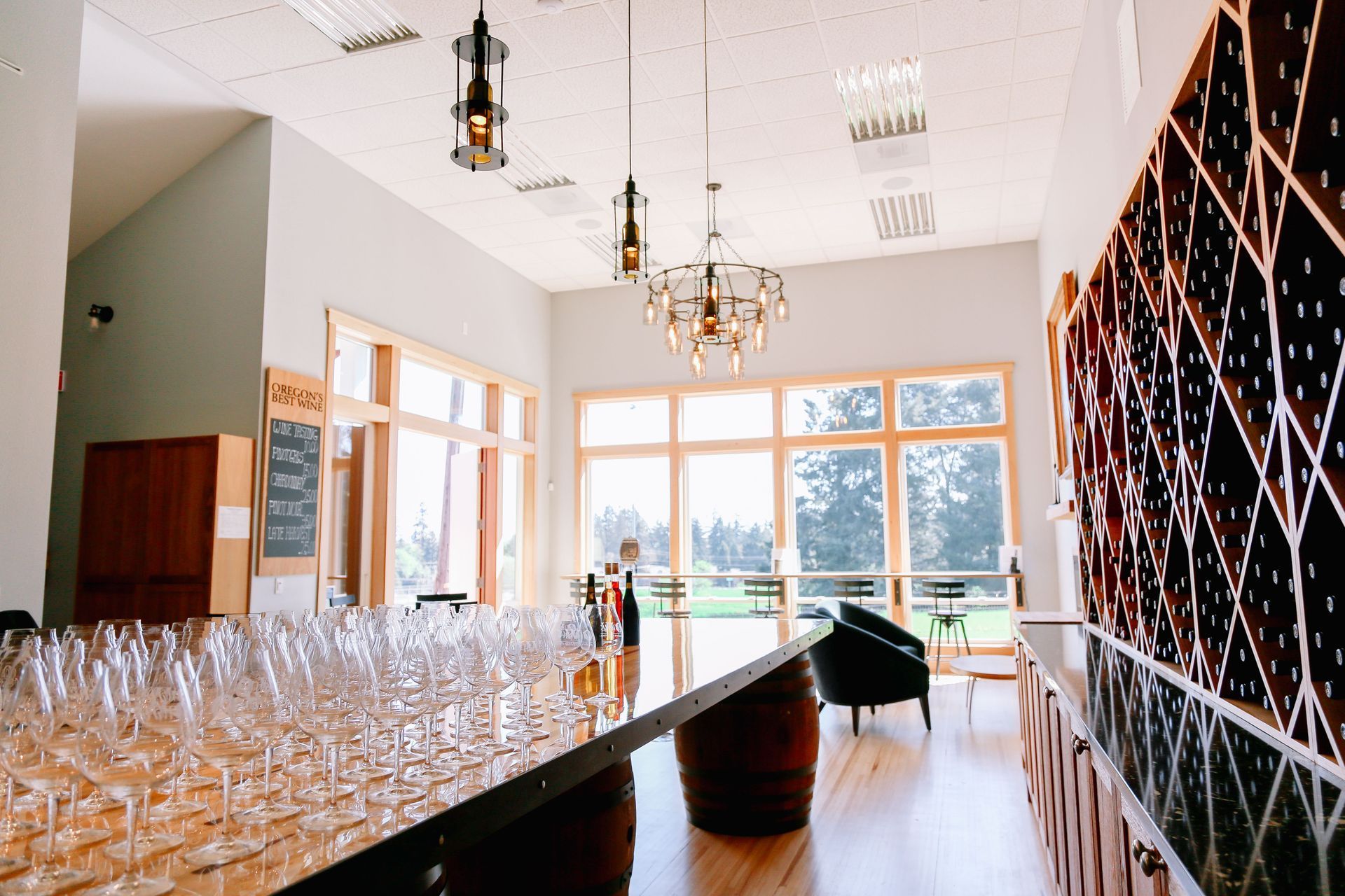 Tasting Room Interior, View from behind the bar looking over tasting room with wine glasses on the counter and bottles stored behind the counter