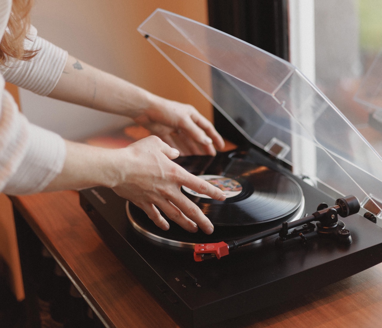 A person putting on a vinyl record at the Domaine Lumineux Tasting Room