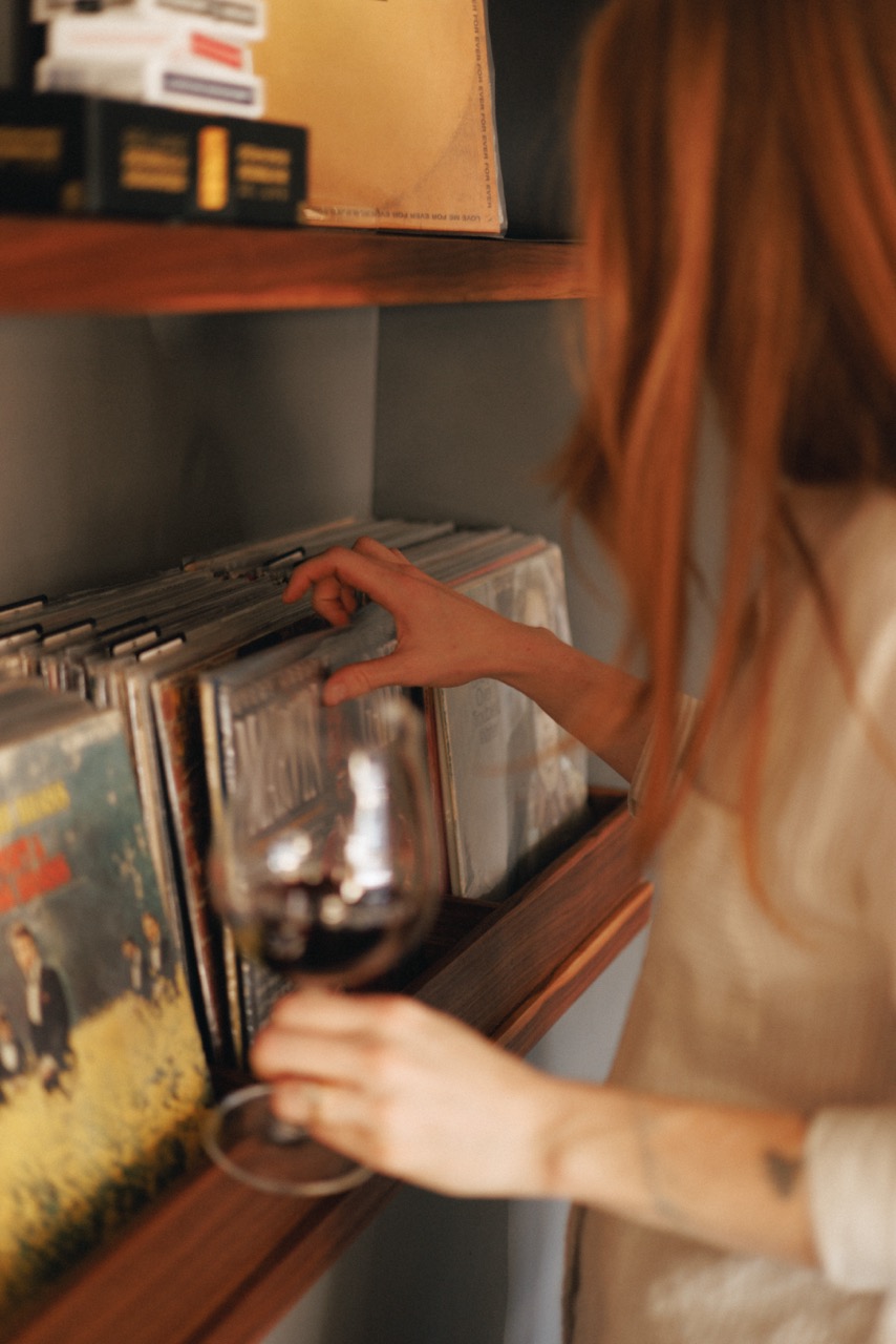 A person browsing through vinyl; records at the Domaine Lumineux Tasting Room.