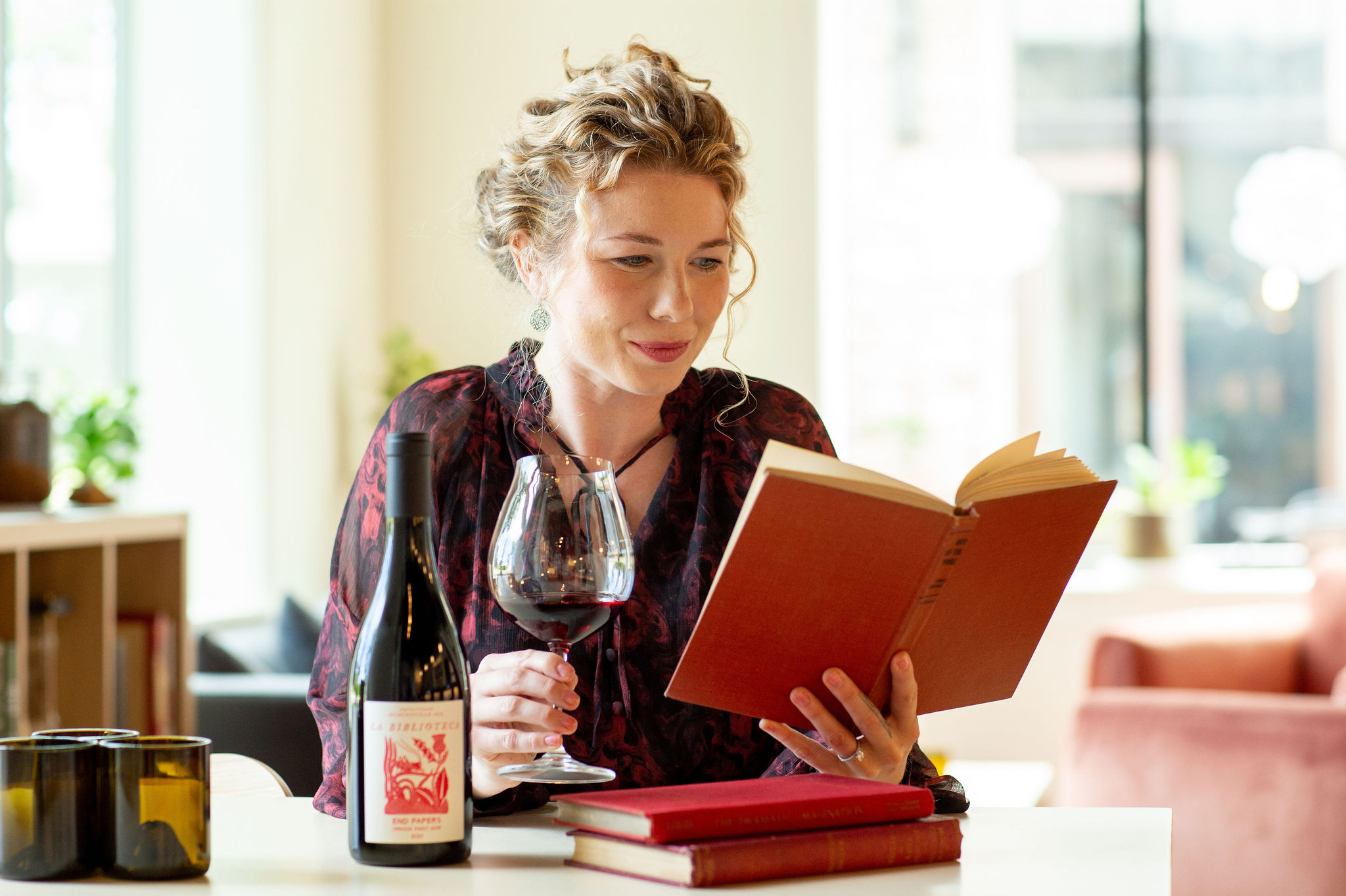 a woman reading and holding a glass of our wine