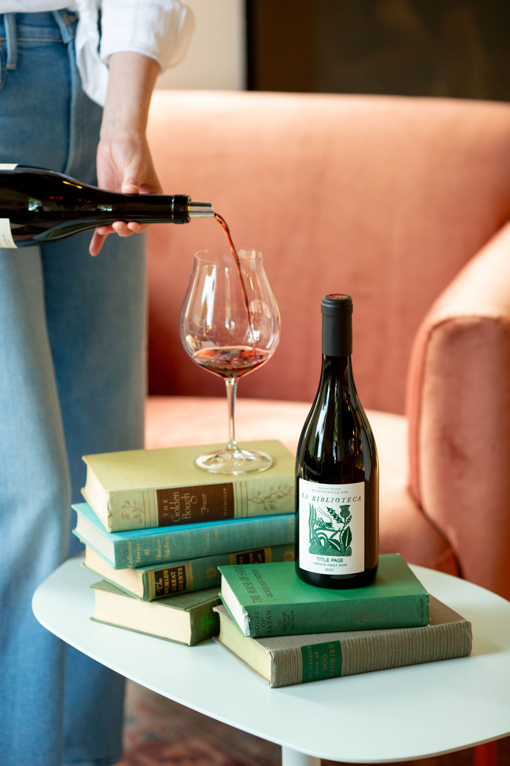 a bottle of Title Page Pinot Noir being poured amongst books