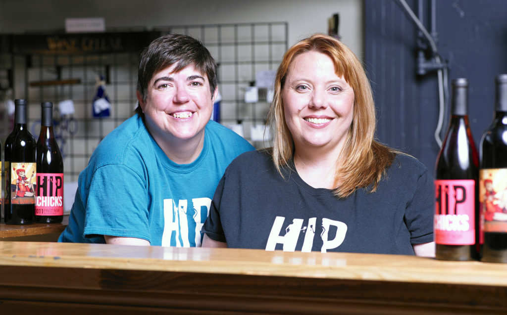 Two people seated behind a bar smiling at the camera